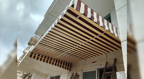 Striped fabric awning installed beneath a residential balcony