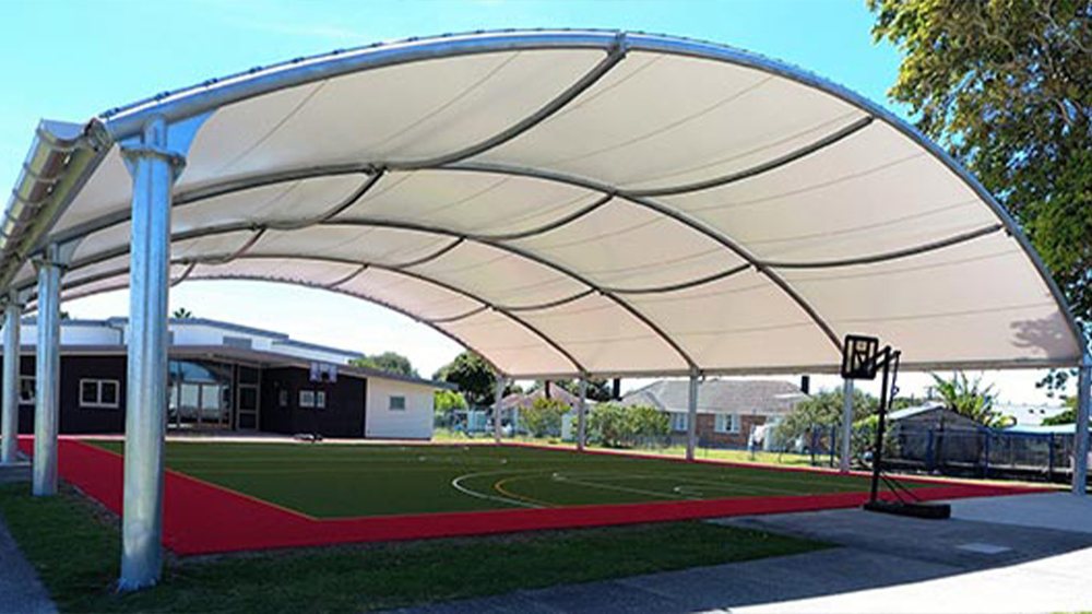 Freestanding tensile canopy shading an open outdoor court area